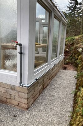 De waterleiding buiten om de kas en de grond met grind.