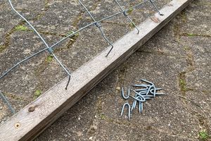 De omgebogen draadeinden in de gaten steken en vastzetten met krammen.