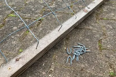 Umgebogene Drahtenden in die Löcher einschlagen, mit Stahlkrampen fixieren.